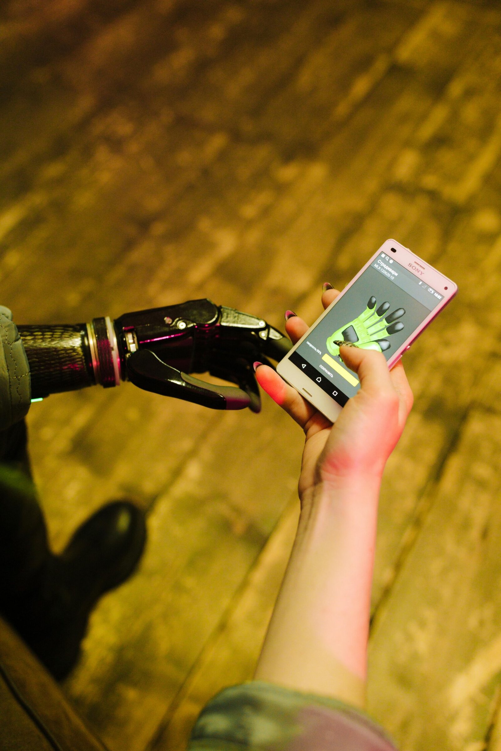 Close-up of a robotic hand being controlled by a smartphone app indoors.